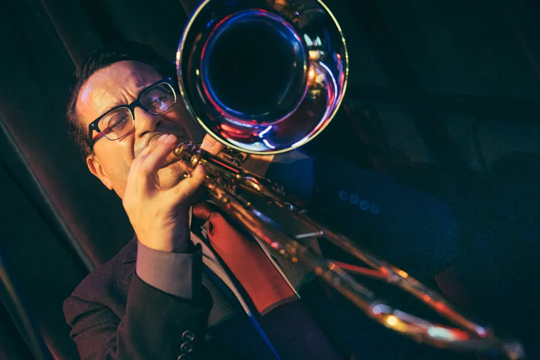Guajirón trombonist performing under blue and red stage lights